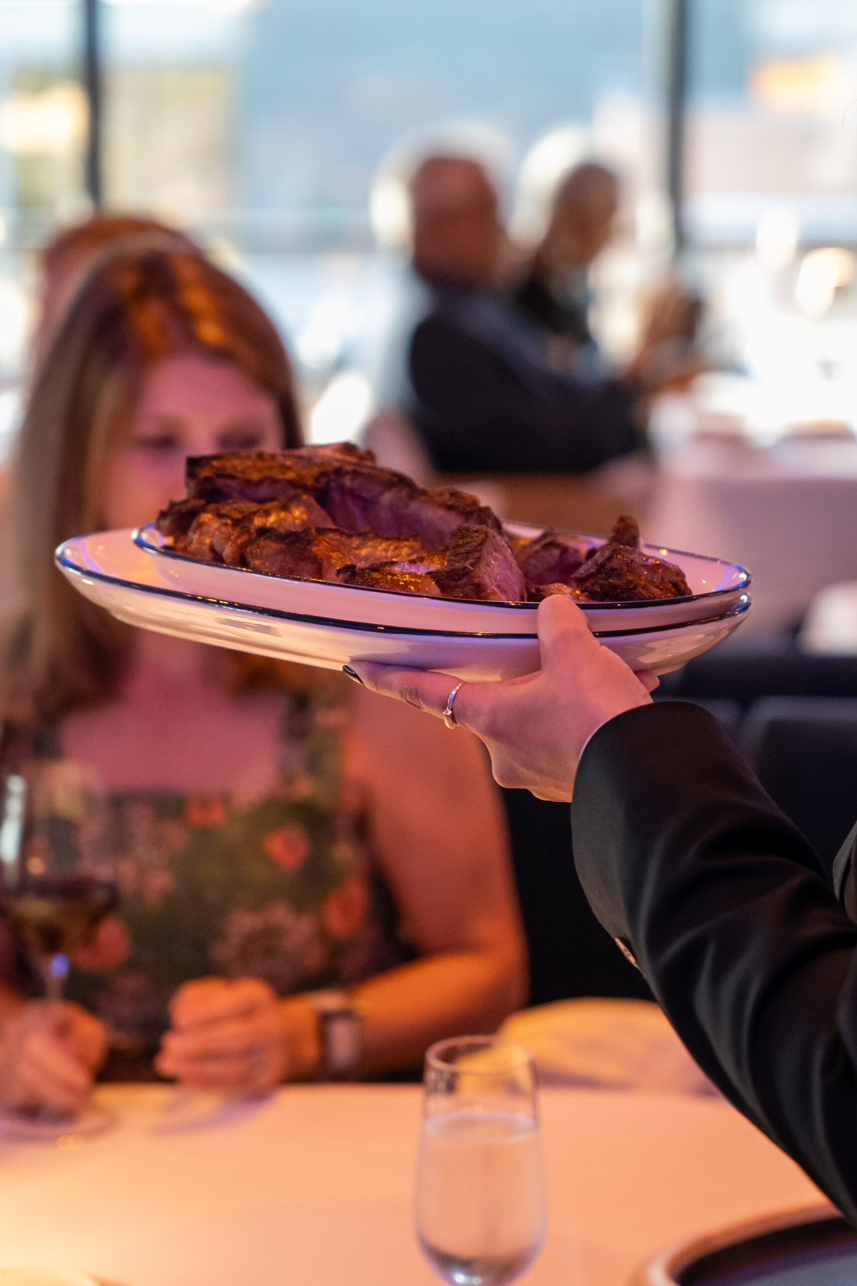 A server setting down a plate with a 32 oz porterhouse on it