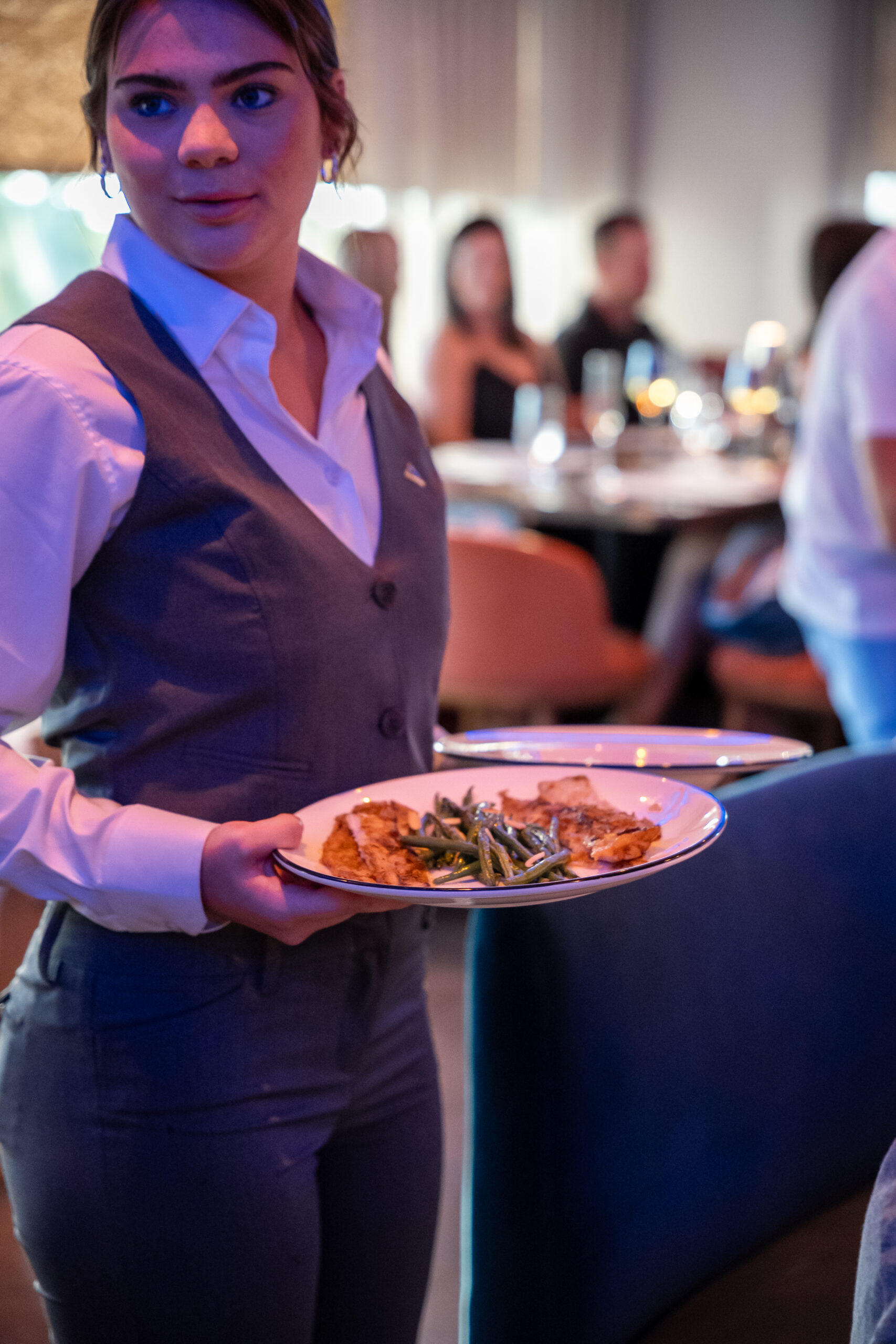 A servers assistant holding a plate of dover sole with haricot verts